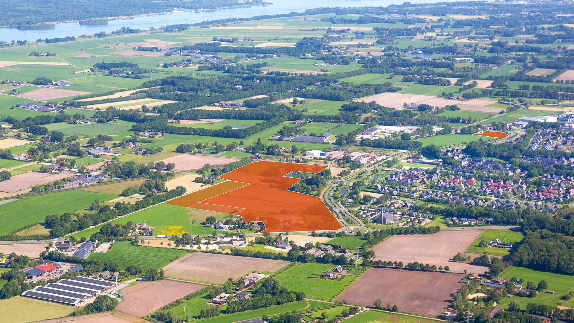 Luchtfoto plangebied Henslare van een landelijk gebied met weilanden, landbouwpercelen, wegen en bebouwing. Enkele gebieden zijn met een oranje vlak gemarkeerd.